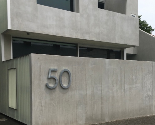 Industrial style concrete house with large number 50 mounted to a concrete fence