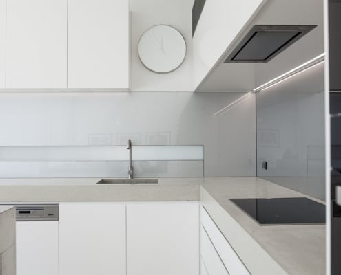 White minimalist kitchen with stone bench tops and induction stovetop