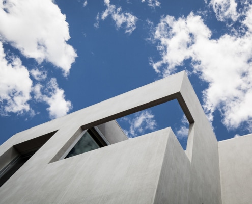 View of concrete facade looking up towards the sky with small open area balcony