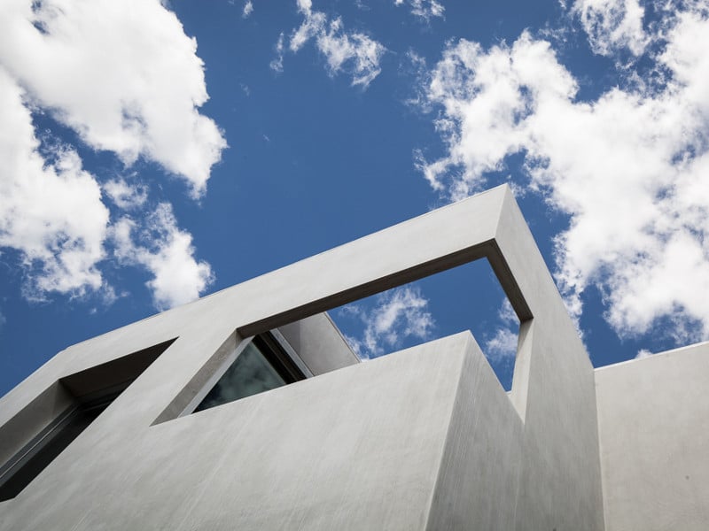 View of concrete facade looking up towards the sky with small open area balcony
