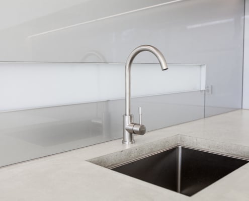 Minimalist kitchen sink with stone bench top and glass splash back