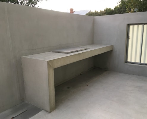 Built in minimalist concrete bench with built in barbecue in concreted outdoor area