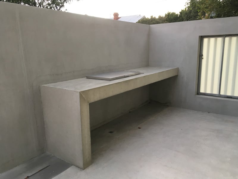 Built in minimalist concrete bench with built in barbecue in concreted outdoor area
